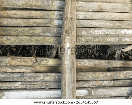 A rustic background texture of an old, weathered, and decaying floor or surface made from traditional bamboo slats.