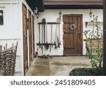 Rustic backyard with a barn. Whitewashed walls and traditional style wooden doors. Garden tools hanging on the wall. A tinted photograph with a photographic film effect. Horizontal photo