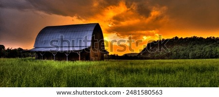 A rustic barn against a dramatic sunset sky