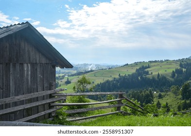 Rustic barn set against breathtaking green hills and valleys, under a bright blue sky. Perfect for themes of nature, peace, and simplicity. Carpathian Mountains, Ukraine - Powered by Shutterstock