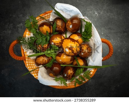 Rustic basket with naturally dyed Easter eggs and green leaves