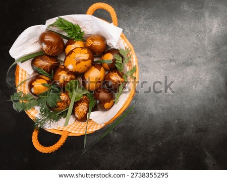 Rustic basket with naturally dyed Easter eggs and green leaves