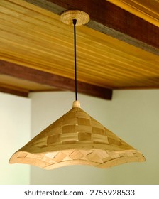 Rustic and bohemian interior decor featuring a handcrafted woven rattan pendant light fixture. Hanging from a warm wooden ceiling, this lighting element adds a touch of natural, tropical, or farmhouse style to the room.