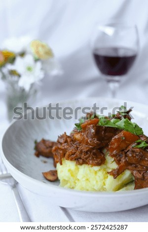 Rustic Braised Beef Stew  - Boeuf Bourguignon - with Mashed Potatoes and Glass of red Wine and Fresh Herbs in a Cozy Setting