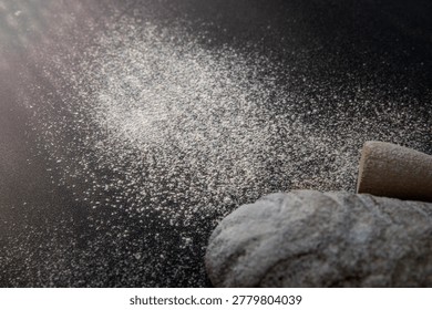 Rustic bread loaf with flour and rolling pin on dark background