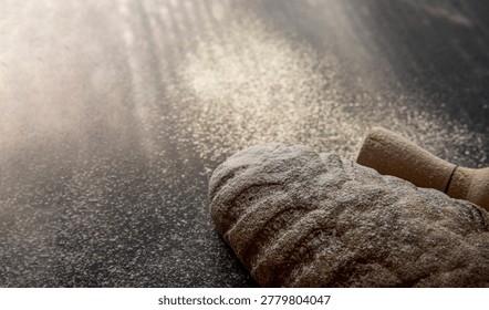 Rustic bread loaf with flour and rolling pin on dark background