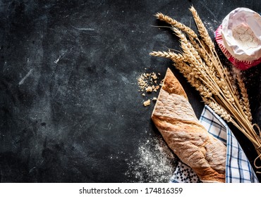 Rustic bread roll or french baguette, wheat and flour on black chalkboard. Rural kitchen or bakery - background with free text space. - Shutterstock ID 174816359
