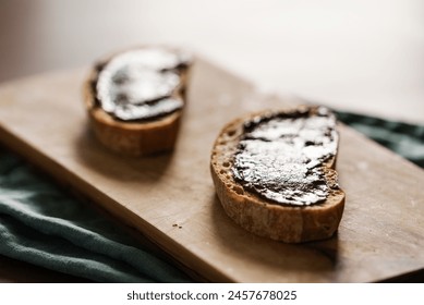 Rustic bread slices with chocolate spread on olive wood board closeup
