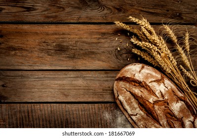 Rustic bread and wheat on an old vintage planked wood table. Dark moody background with free text space. - Powered by Shutterstock