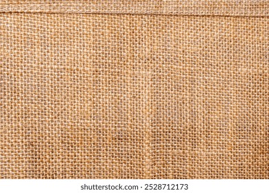 A rustic burlap background with a woven texture. The background is brown, showcasing a natural, earthy brown color and tactile feel. Light brown background. Fabric and textile texture background.