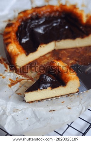 A rustic burnt basque  cheese cake with a deeply caramelized, almost charred top that contrasts beautifully with its rich and creamy interior. The surface is dark and glossy, giving a signature smoky sweetness, while the edges are slightly crispy and golden. Baked on parchment paper, this cheesecake has a soft, custard like center that melt in every bite, offering a perfect of bittersweet and creamy flavors