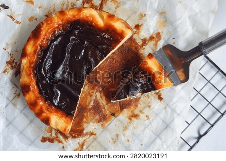 A rustic burnt basque  cheese cake with a deeply caramelized, almost charred top that contrasts beautifully with its rich and creamy interior. The surface is dark and glossy, giving a signature smoky sweetness, while the edges are slightly crispy and golden. Baked on parchment paper, this cheesecake has a soft, custard like center that melt in every bite, offering a perfect of bittersweet and creamy flavors