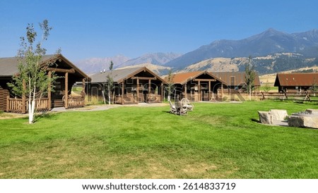 Rustic cabins surrounding a fire pit with mountain views in Paradise Valley, Montana.