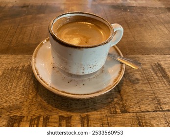 A rustic ceramic cup of espresso on a wooden table in a cozy cafe setting - Powered by Shutterstock