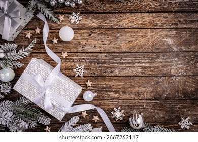 Rustic Christmas background with gift boxes tied with white ribbon and snow fir branches on vintage wooden table. Ideal for holiday cards, seasonal banners, and festive designs.