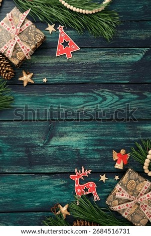Rustic Christmas flat lay with pine branches, pinecones, wooden stars, and beads on teal wood table. Top view, Xmas vertical background.