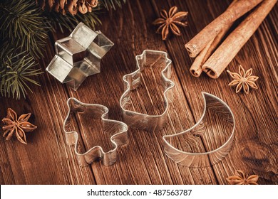 Rustic Christmas wooden background with cookies cutters, fir tree and cinnamon sticks. Shallow focus