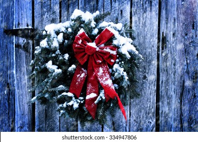 Rustic Christmas Wreath On Old Weathered Barn In A Snow Storm.