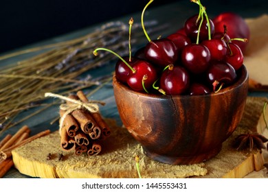 Rustic Composition of Cherries in wooden bowl on blocks of wood and crat paper. ingedient for cherry desert. Summer dieting.