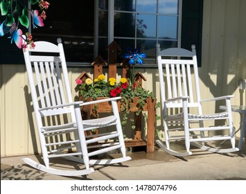 Rustic, Country Style Front Porch Seating With White Rocking Chairs And Fresh Flowers