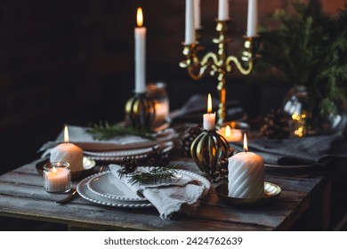 Rustic elegant table decor for christmas family dinner. Center piece with white candle, pine cone, fir tree branches. Zero waste eco-friendly home decoration. Cozy atmosphere, wooden background. - Powered by Shutterstock