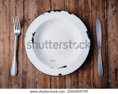 
rustic empty plate demonstrating hunger on wooden background.