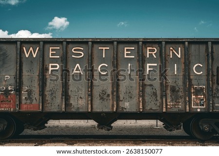 Rustic freight train car with 'Western Pacific' text against cloudy sky.