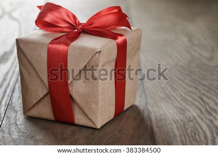 rustic gift box with red ribbon bow, on old wood table