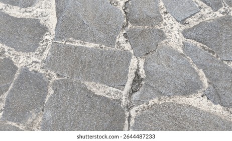 Rustic grey flagstone paving with irregular shapes and rough textures, set with light-colored mortar, forming a durable and natural outdoor surface..