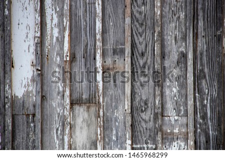 Rustic grey worn board and batten vertical siding background with white paint remnants