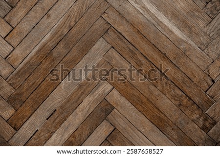 A rustic herringbone pattern made of aged wooden planks evokes a cozy atmosphere.