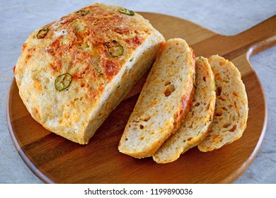 Rustic Homemade Bread With Jalapeno Peppers And Cheddar Cheese On Round Bread Board In Horizontal Format. 