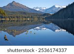 Rustic homes rim the shores of mirror-like Auke Lake surrounded by towering mountain peaks, Juneau, Alaska