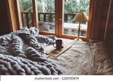 Rustic interior decoration of log cabin bedroom. Cozy warm blanket on bed by window. - Shutterstock ID 1230703474