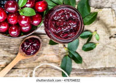 Rustic jar with cherry jam and fresh cherries in a bowl, homemade preserves, overhead