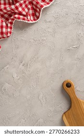 Rustic kitchen composition for cooking and preparation with red gingham cloth and wooden cuttingboard on a textured concrete background offering empty space for recipe styling