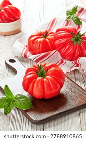 Rustic kitchen scene with empty wooden cutting board and fresh heirloom tomatoes