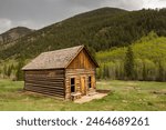 A rustic log cabin with mountains in the background.