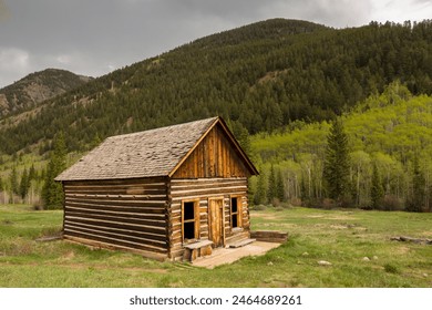 A rustic log cabin with mountains in the background. - Powered by Shutterstock