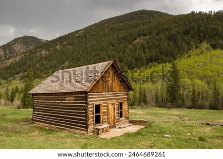 A rustic log cabin with mountains in the background.