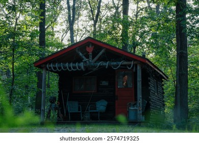  A rustic log cabin surrounded by trees with a stunning sunset in the background. This serene, nature-filled scene captures the peaceful beauty of a cabin retreat in the woods.