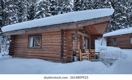 Rustic log cabin surrounded by deep snow and evergreen forest on a winter day.