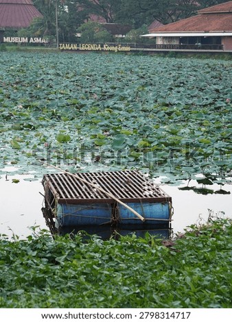 A rustic makeshift raft made from blue plastic barrels and metal grating sits peacefully upon the calm dark water surface.