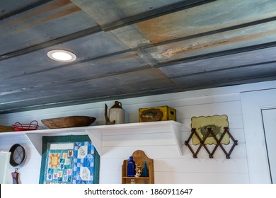 A Rustic Metal Ceiling In A Small Hunting Cabin With White Shiplap Walls For A Farmhouse Style