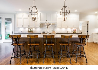 rustic modern farmhouse kitchen with white cabinets wrought iron and wood chairs eating counter and light fixtures