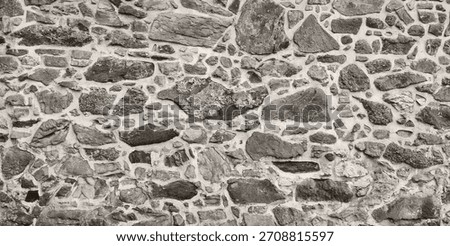 Rustic Natural Stone Wall Texture Background. Irregular Granite and Quartzite Rocks Pattern with Mortar Joints for Architectural and Historical Backdrop