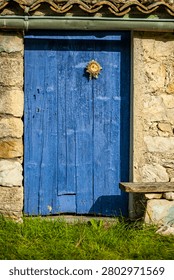 Rustic old blue door featuring a traditional eguzkilore ornament on a stone wall