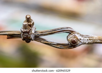 Rustic old steel cable loop, clamp, and bolts with faded, chipped paint against soft focus blurred background