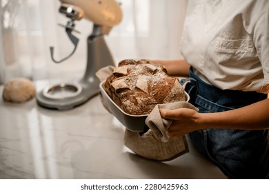 rustic organic loaf of bread in hands of woman baker. Homemade bread food photography. Cropped photo - Powered by Shutterstock