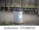 Rustic outdoor setting featuring a trash barrel at a picnic area.